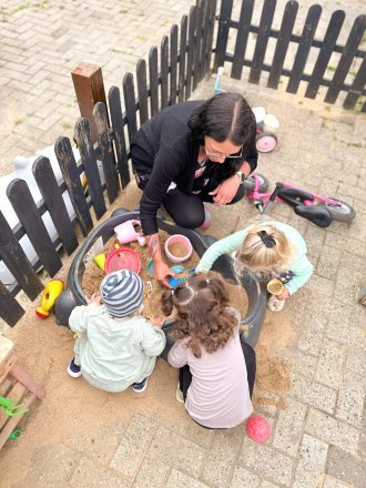 Varina spielt mit Kindern im Sandkasten im Hof