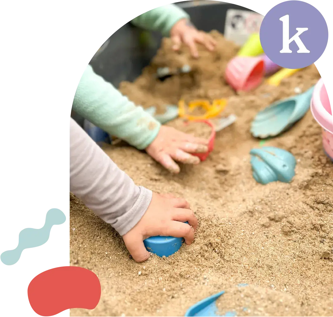 Kinder spielen gemeinsam mit bunten Schaufeln und Förmchen im Sandkasten